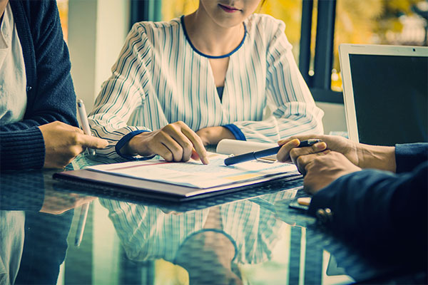 Mans hand holding pen resting on a POINT Strategy and Business School file and notes.